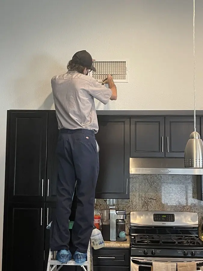 Technician inspecting an air vent during HVAC service in Peabody